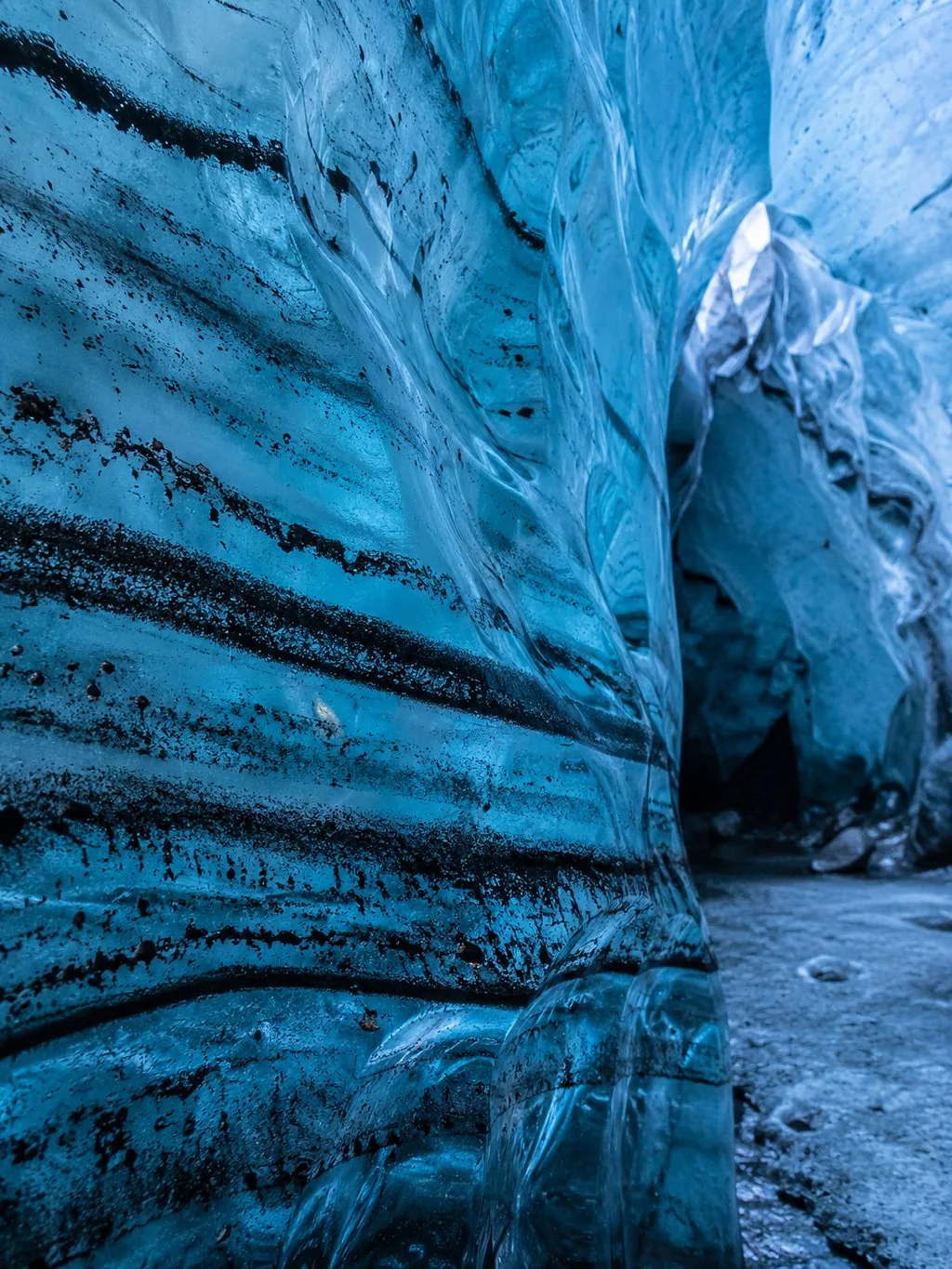 Close-up of black volcanic ash layers streaking through glacier ice